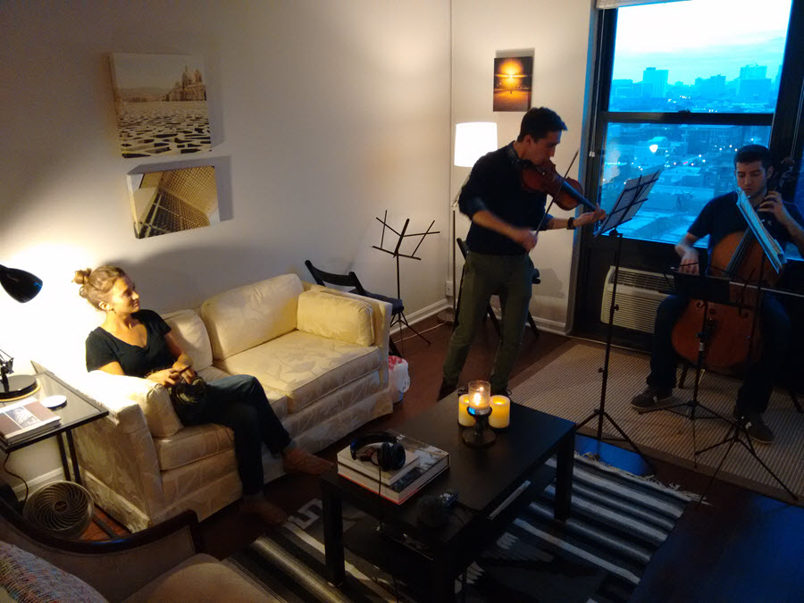 Cassandra Yarnall (left) listens as GroupMuse musicians rehearse ahead of a performance. She hosted a concert in her Logan Square apartment.